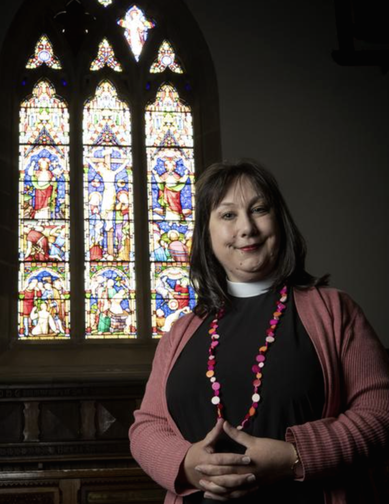 Rev. Mother Emily Fraser standing stage left of the East Window of All Saints Church